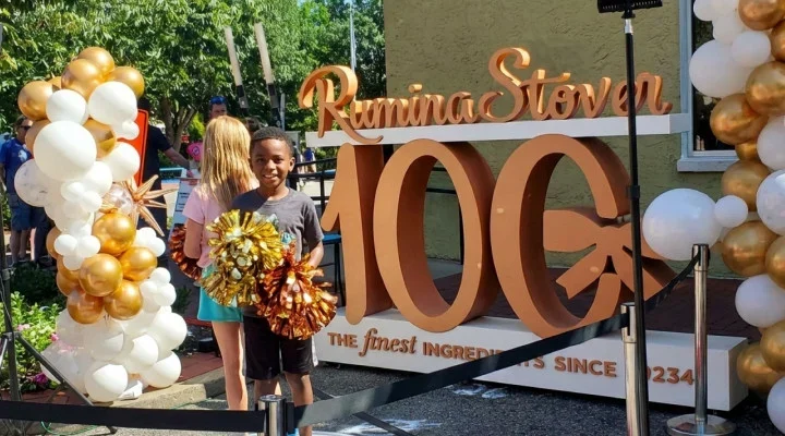 custom 3d gold dimensional lettering for russell stover anniversary signage child with gold pom poms at the russell stover 100th anniversary celebration 2